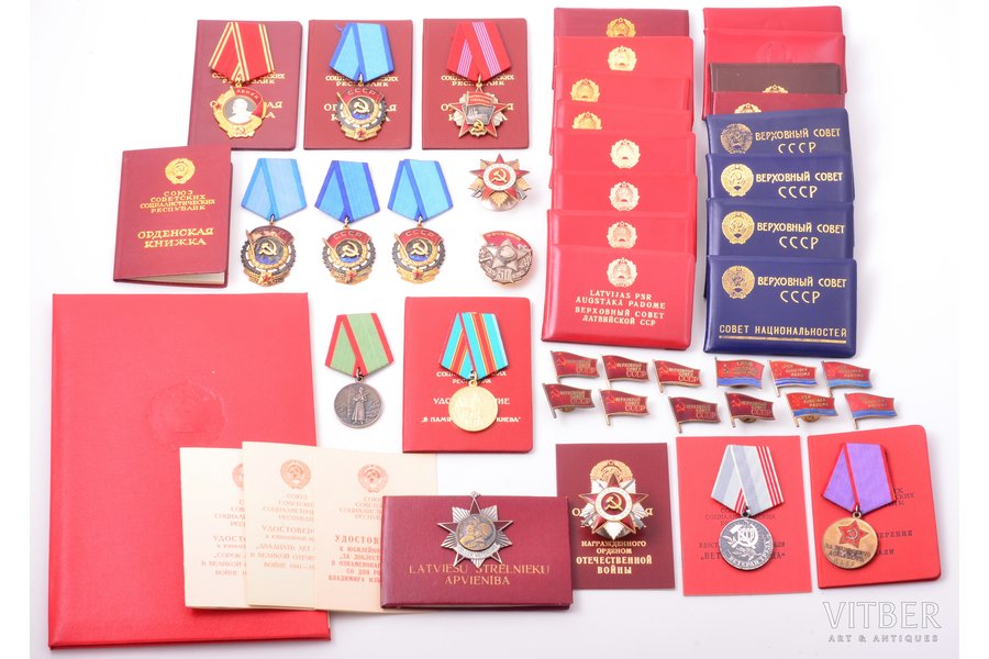 set of awards and documents, awarded to P.S., Chairman of the Presidium of the Supreme Council of the Latvian SSR. The set includes: order of Lenin, № 432594 with document (1979); The Order of the Patriotic War, 1st class, № 311340, with document; 5 deputy badges of the Supreme Council of the Latvian SSR: № 1, 3, 112, 141, 1 badge without number; 7 documents, issued by the Supreme Council of the Latvian SSR, 3 documents, issued by the Council Ministers of the Latvian SSR; 7 deputy badges of the Supreme Council of the USSR: № XI-300, 309, 309, 319, 319, 2 badges without numbers; 6 documents, issued by the Supreme Council of the USSR; 3 Orders of the Red Banner of Labour: № 130249 (enamel defect), № 373974, № 414099, with document (1950); Orders of the Red Banner of Labour № 641011, with document (1971); Order of the October Revolution Nº 2078 with document (1973); medal "For Distinction in Guarding the State Border of USSR"; medal "In Commemoration of the 1500th Anniversary of Kiev", with document - custom made cover (1982); Honorary Diploma of the Presidium of the Supreme Council of the Latvian SSR (1989); other awards and documents (see on photo), USSR